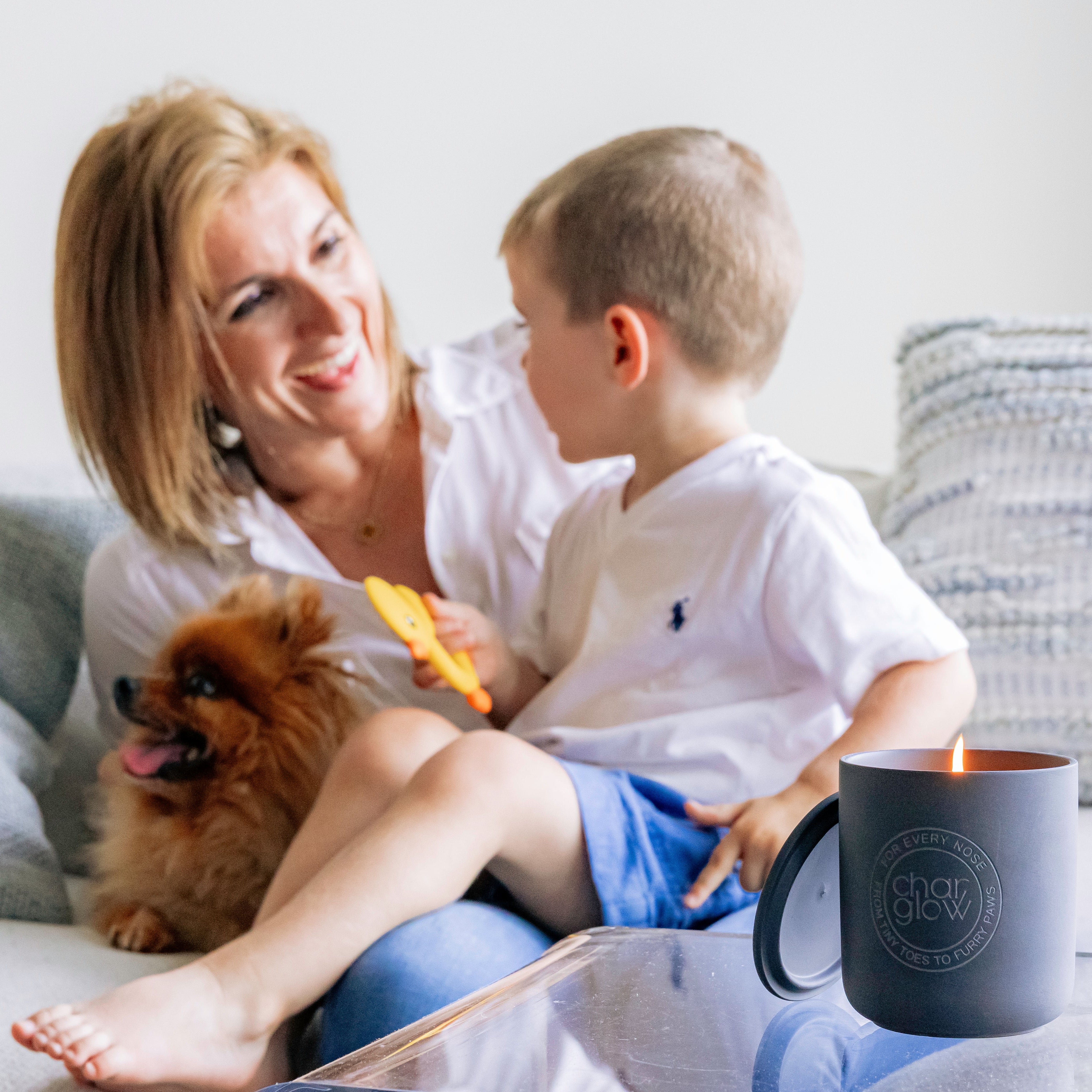 mom with a baby and a dog with a pet a baby friendly candle burning in foregraound