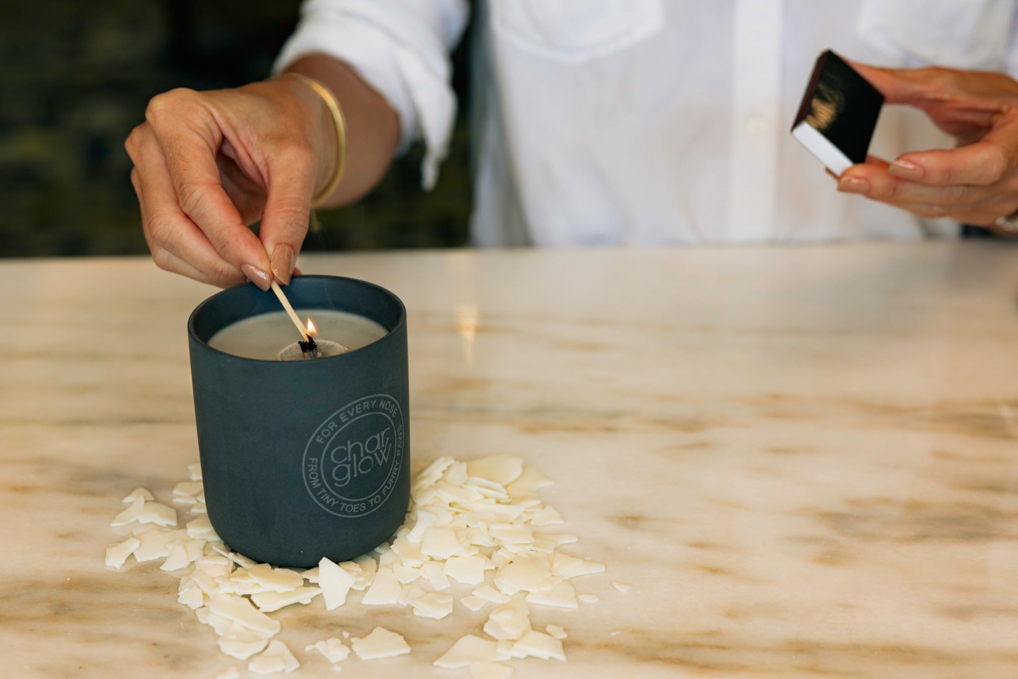 CharGlow candle being hand-lit in its charcoal ceramic vessel during the candle-making process
